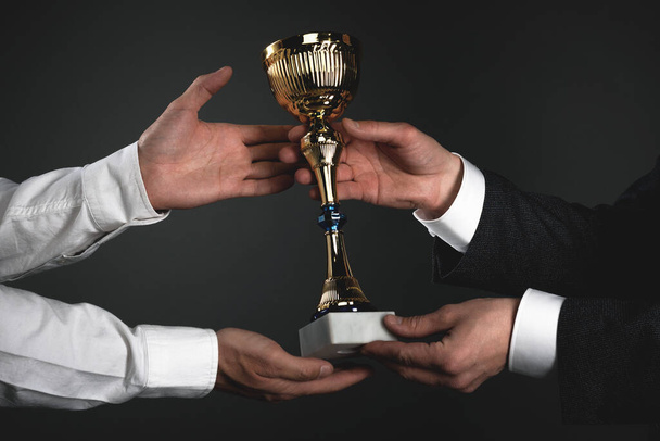 Award ceremony concept. Businessman is giving a golden cup award trophy to a winner. First place background. Best worker reward. Business achievement. - Fotó, kép