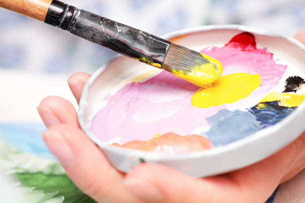 Yellow gouache paint and paint brush close up abstract background. - Foto, afbeelding