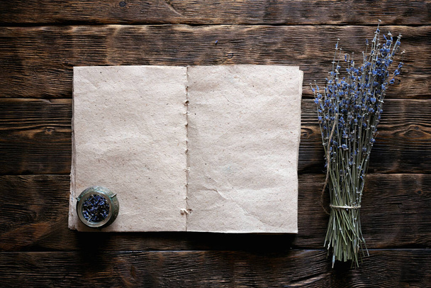 Dried lavender flower branch and a blank aromatherapy recipe book mock up on a wooden table background with copy space. Herbal medicine concept. - Photo, Image