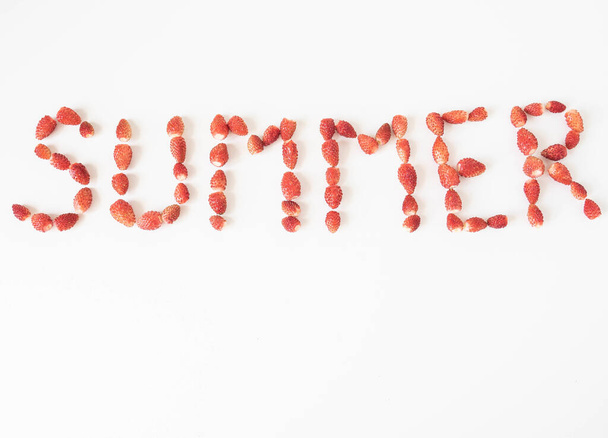 Palabra de verano creada a partir de fresas silvestres frescas maduras sobre un fondo blanco. Vista superior. espacio de copia
 - Foto, Imagen