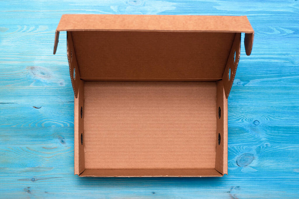 Open parcel cardboard box on a blue wooden table background. Delivery service concept. - 写真・画像