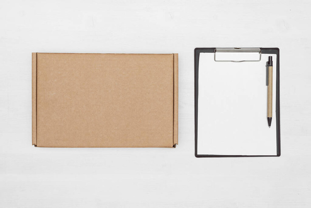 Blank cardboard parcel box and an empty invoice document mock up on a white table background. - Foto, immagini