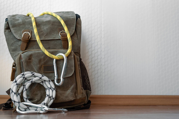 A backpack with safety rope and carabiners on a white wall background . Travel or adventure background. - Fotografie, Obrázek