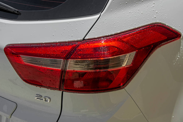 Close-up mokré čisté a v dobrém stavu bílé auto červené koncové světlo s kapkami vody. Signál čirého skla otočit a zpětná světla osvětlená slunečním světlem s kopírovacím prostorem. Podrobnosti exteriéru - Fotografie, Obrázek