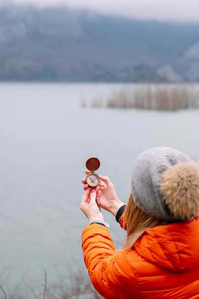 A tourist woman in hat and coat with a compass in nature - Photo, Image
