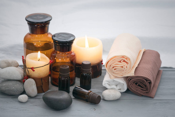 Aromatherapy oil bottles, towel and burning candles on a wooden table. Spa concept background. - Foto, imagen