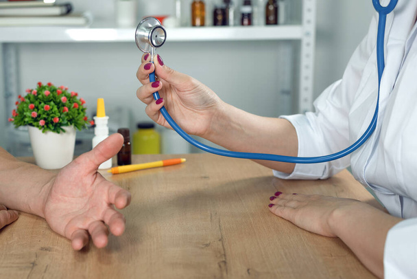 Therapist listening a patient complaints about his health and prepare a stethoscope. Doctor visit. - 写真・画像
