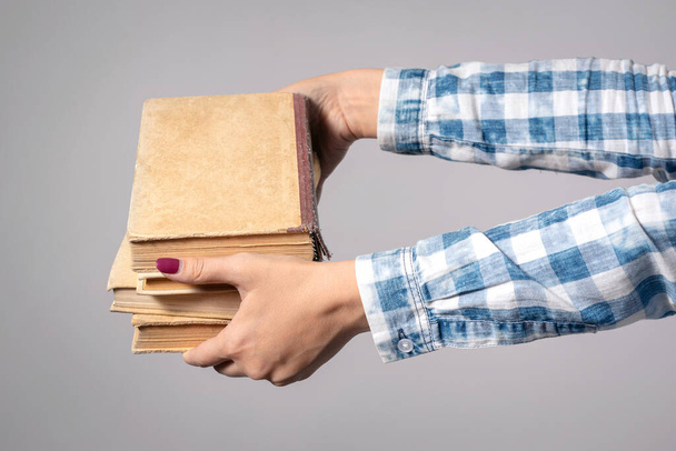 Stack of books in female hands isolated on gray background. - Photo, image
