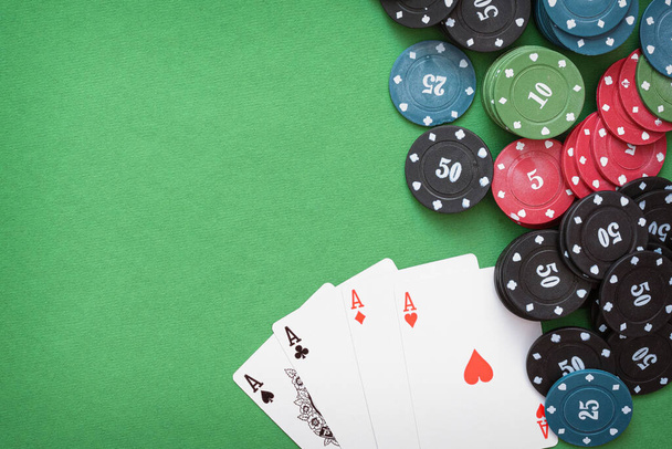 Four aces cards and poker chips on the green table background with copy space. - Photo, image