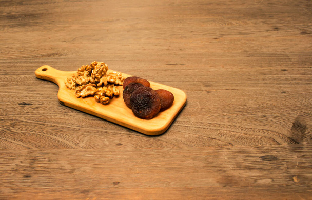 Орех и абрикос в деревянном блюде на деревянном фоне
 - Фото, изображение