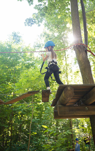 Aventura de corda - uma menina andando em uma ponte de corda com cinto de seguro
 - Foto, Imagem