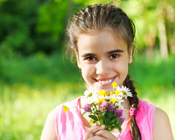 Close up portrait of little smiling girl with spring flowers - Foto, imagen