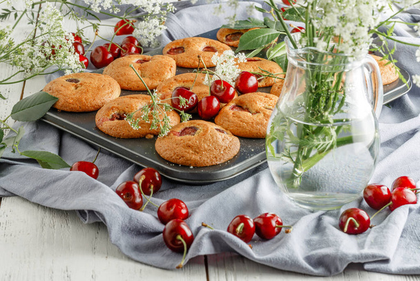 Homemade cherry muffins and fresh cherries on a light background. Delicious dessert - Foto, Imagen
