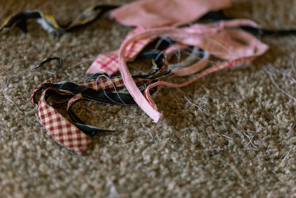 Stofffetzen auf dem Boden schwarzer kastanienbrauner karierter rosa karierter weißer Faden - Foto, Bild