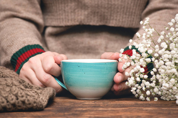 Woman in warm sweater drinking a hot tea close up background. - Fotografie, Obrázek