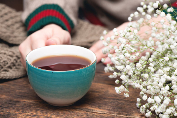 Woman in warm sweater drinking a hot tea close up background. - Foto, Imagen