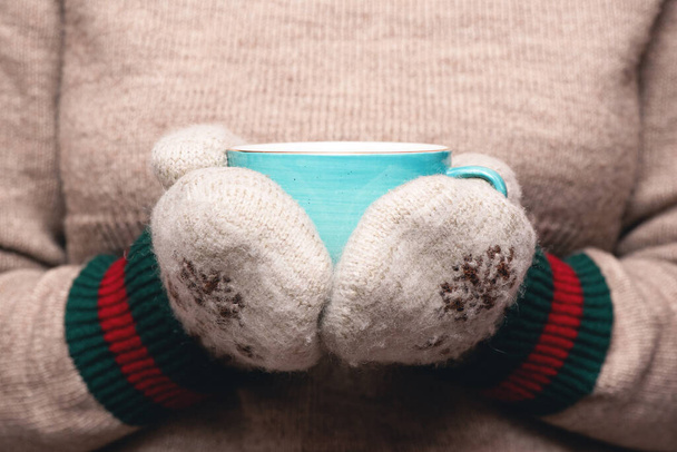 Woman in warm sweater and mittens is drinking a hot tea close up background. - Fotografie, Obrázek