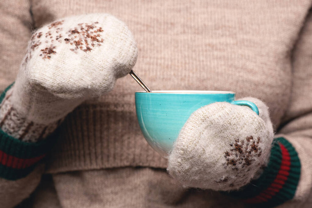Woman in warm sweater and mittens is drinking a hot tea close up background. - Foto, Imagen