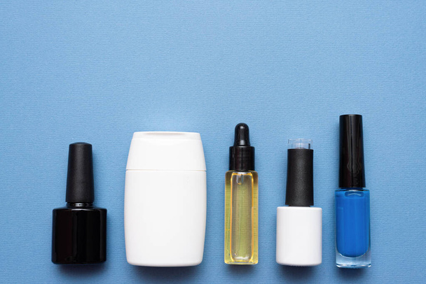 Nail polish, micellar water and cuticle oil bottle on blue background with copy space. - Fotografie, Obrázek
