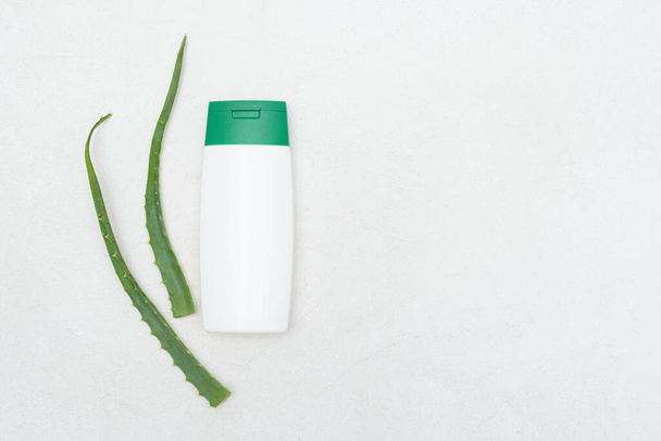 Aloe vera shampoo and green plant leaves on white background. - Фото, изображение
