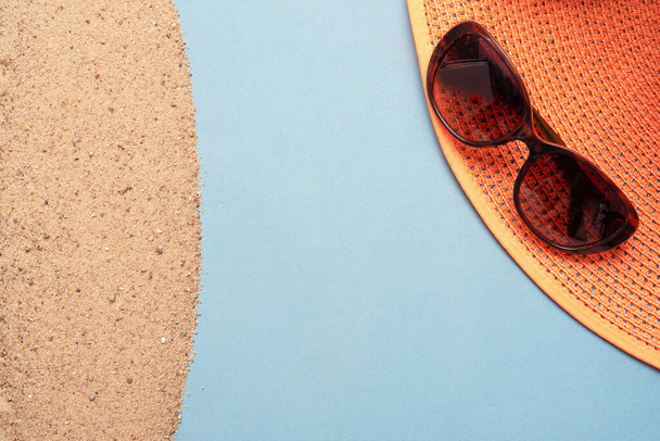 Beach accessories on the sand over blue background with copy space. Summer vacation concept. - Valokuva, kuva