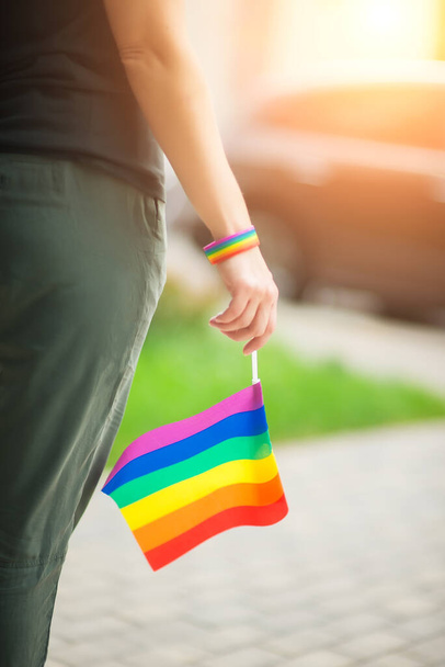 Женская рука в гей-браслете гордости с радужными флагами. ЛГБТ-люди, однополые отношения и гомосексуальные концепции
  - Фото, изображение