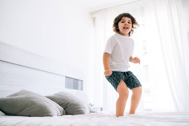child jumping in bed for fun during covid 19 - Photo, Image