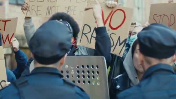 Jonge multi-etnische mannelijke en vrouwelijke studenten schreeuwen en schreeuwen tegen politieagenten tijdens demonstratie voor mensenrechten VS demonstranten vechten en kibbelen met agenten bij protest tegen geweld en racisme - Video