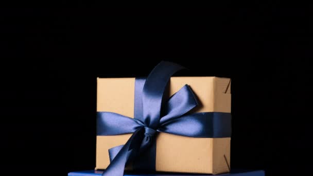 Подарок, завернутый в коричневую крафт-бумагу и завязанный голубой шелковой лентой, вращается вокруг своей оси на черном фоне
 - Кадры, видео