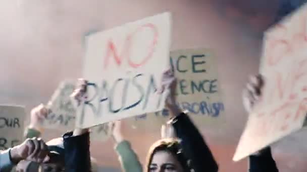 Běloška s plakátem V davu demonstrantů nestojí rasismus a v noci volá po rovných lidských právech. Ženské protestantky na manifestu v USA v kouři Koncept vzpoury - Záběry, video