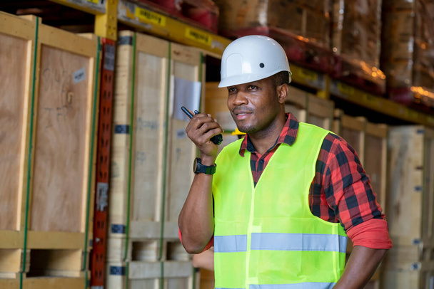 Warehouse worker using handheld radio receiver for communication in a large warehouse. - Photo, Image