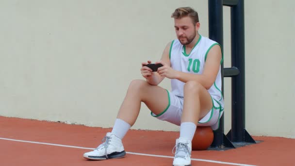 Basketball Fan Reaction Concept - Giocatore di basket deluso in costume da basket guardando la sua squadra preferita su uno smartphone, 4k rallentatore - Filmati, video
