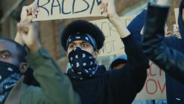 Acercamiento de jóvenes estudiantes de razas mixtas con máscaras en las caras de pie en la multitud con carteles y protestando contra el racismo y la violencia. Multiétnica multitud en manifestación en EE.UU.
. - Metraje, vídeo