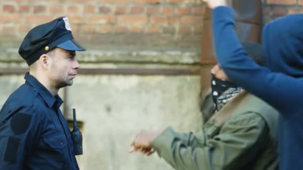 Oldalnézet a kaukázusi rendőrről és az afro-amerikai férfi tüntetőről maszkkal az arcán és veszekedés az utcán a megnyilvánulás alatt. Rendőrség és vegyes fajú tüntetők konfliktusa. - Felvétel, videó