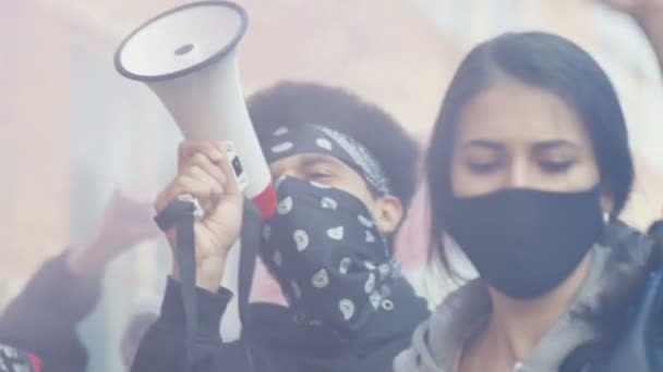 Acercamiento de rostros de jóvenes manifestantes de razas mixtas masculinas y femeninas con máscaras gritando y gritando lemas en una manifestación en Estados Unidos contra el racismo y la violencia. Estudiantes en protesta con demandas
. - Metraje, vídeo