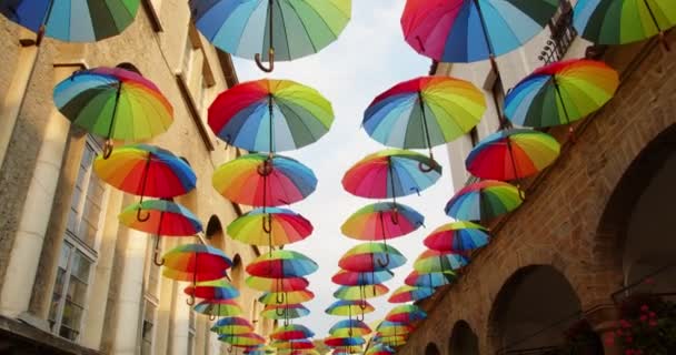 Şehir caddesinin üzerinde gökyüzünde renkli şemsiyeler açık. Dekorasyon olarak, 4K - Video, Çekim
