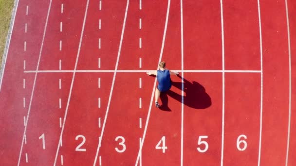 Widok z góry biegacza na torze sportowca na linii startu na torze stadionu, 4k - Materiał filmowy, wideo