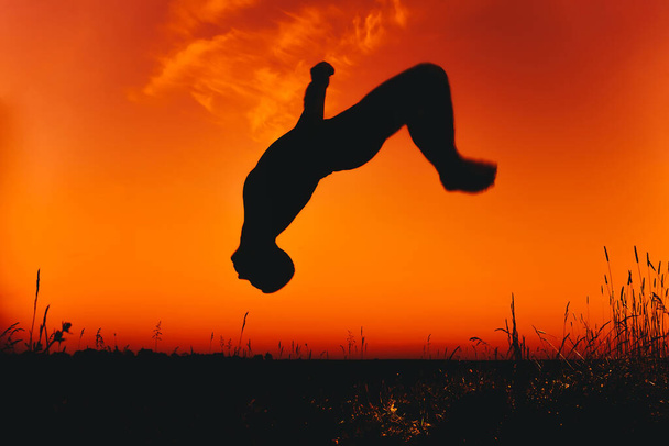 Homme athlète saute et fait des sauts périlleux dans la nature en été - Photo, image