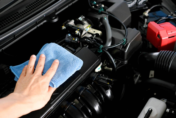 рука мужчины, держащего синюю ткань, заботящегося, обслуживающего автомобиля и уборки и машинного отделения
 - Фото, изображение
