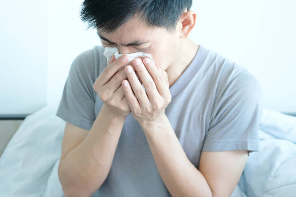 L'homme malade est grippé, utilisant une serviette en papier et il a un nez qui coule. Et il était recouvert de vêtements chauds.Concept de santé - Photo, image