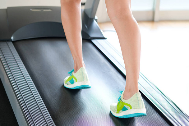 noga kobiety biegającej na bieżni w siłowni, która biegnie wysportowana przez buty do biegania. Koncepcja zdrowia i sportu, - Zdjęcie, obraz
