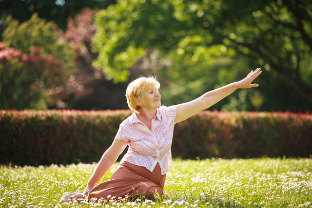 Meditation. Graceful Old Woman in the Park Stretching her Hand - Фото, изображение