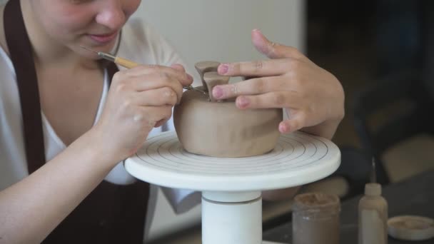 Zamknij żeńskie dłonie trzymając kij i robiąc ozdoby na ceramice. Glinowy produkt do formowania glinki. Pojęcie sztuki ceramicznej i hobby. - Materiał filmowy, wideo