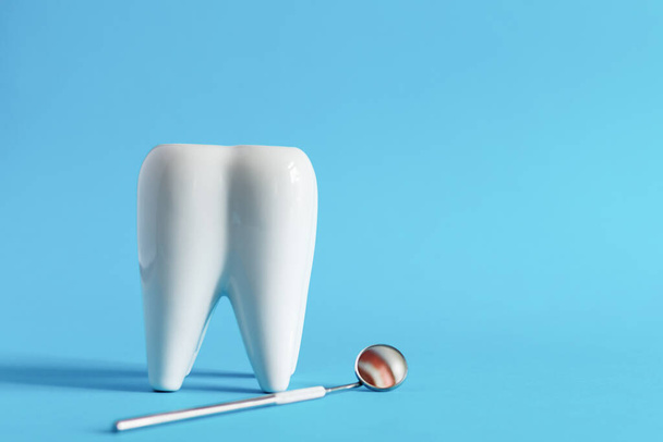 Mavi arka planda diş bakımı için dişçilik aletleri olan beyaz diş modeli. Ağız temizliği konsepti. Boşluğu kopyala. - Fotoğraf, Görsel