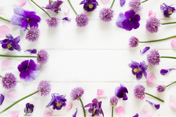 Λουλούδια επίπεδη σχεδίαση, μοβ και ροζ λουλούδια σε λευκό ξύλινο πίνακα, floral πλαίσιο σε επίπεδο lay στυλ με θέση για το κείμενό σας.Πρότυπο για ευχετήρια κάρτα - Φωτογραφία, εικόνα