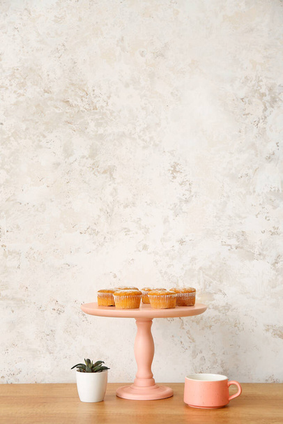 Suporte de sobremesa com bolos e xícara no balcão da cozinha
 - Foto, Imagem