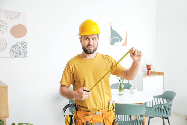 Male carpenter with tape measure in room - Foto, afbeelding