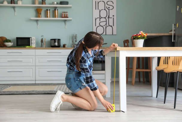 Молода жінка вимірювальний стіл на кухні
 - Фото, зображення