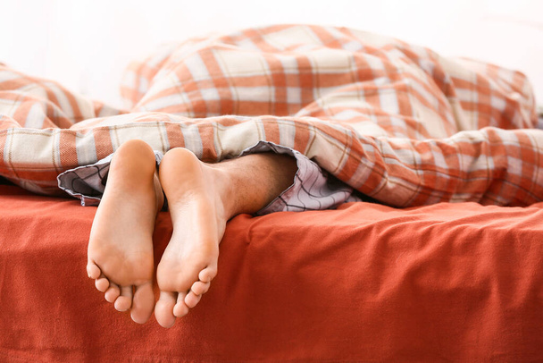 Утро босоногого молодого человека спящего в постели
 - Фото, изображение