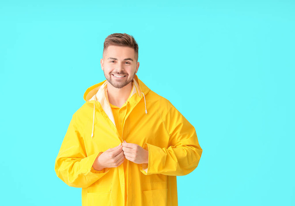 Young man in raincoat on color background - Photo, Image